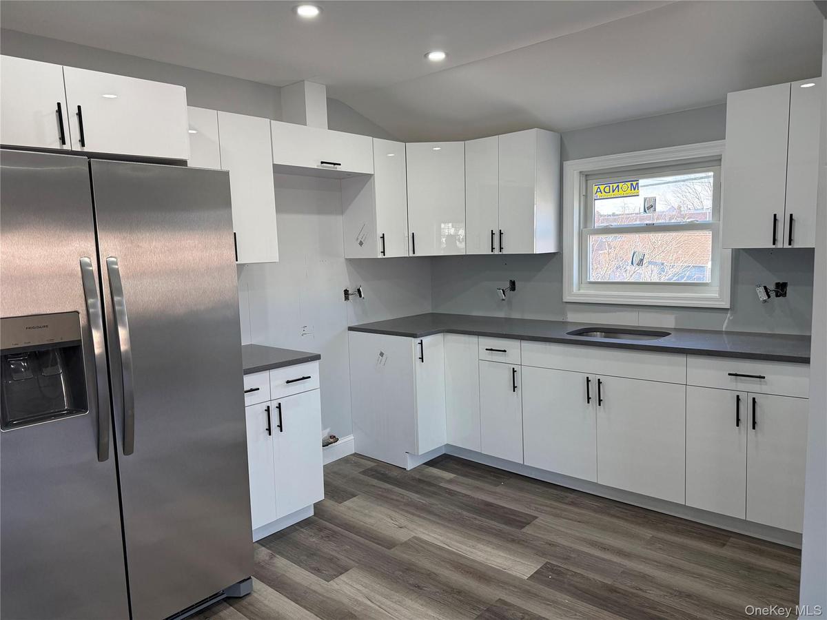 2nd floor Kitchen featuring stainless steel refrigerator with ice dispenser, white cabinets, dark wood-style floors, vaulted ceiling, and recessed lig