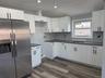 2nd floor Kitchen featuring stainless steel refrigerator with ice dispenser, white cabinets, dark wood-style floors, vaulted ceiling, and recessed lig