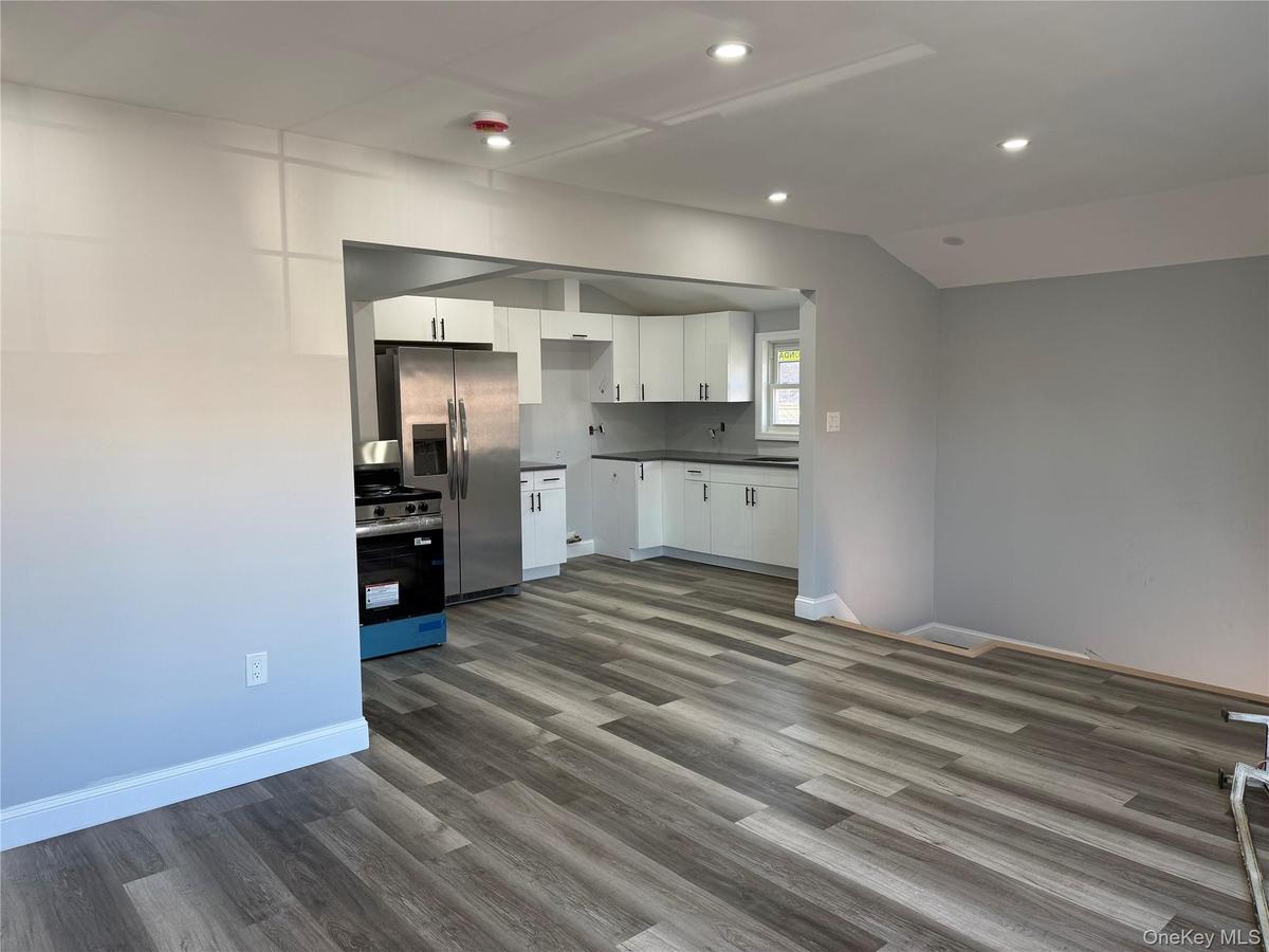 2nd floor living room/Kitchen with white cabinetry, stainless steel appliances, dark wood-style floors, recessed lighting, and dark countertops