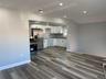 2nd floor living room/Kitchen with white cabinetry, stainless steel appliances, dark wood-style floors, recessed lighting, and dark countertops