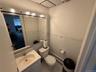 Half bathroom featuring baseboard heating, vanity, light tile patterned flooring, tile walls, and a wainscoted wall