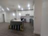 Kitchen featuring white cabinets, backsplash, gray cabinets, a kitchen breakfast bar, and dark wood-style floors