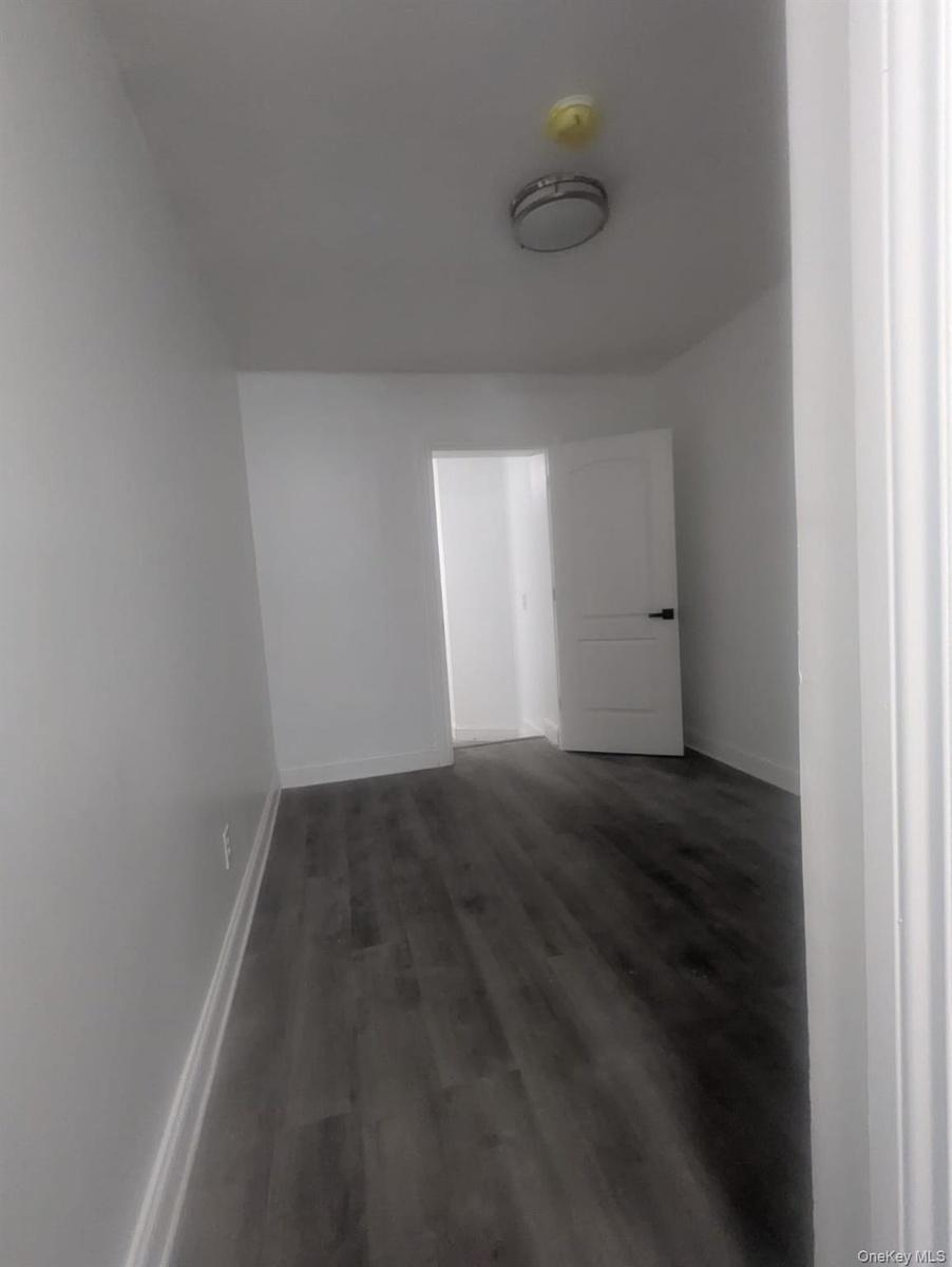 Empty room with dark wood-type flooring and baseboards