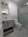 Full bath with vanity, tile walls, a marble finish shower, and wainscoting