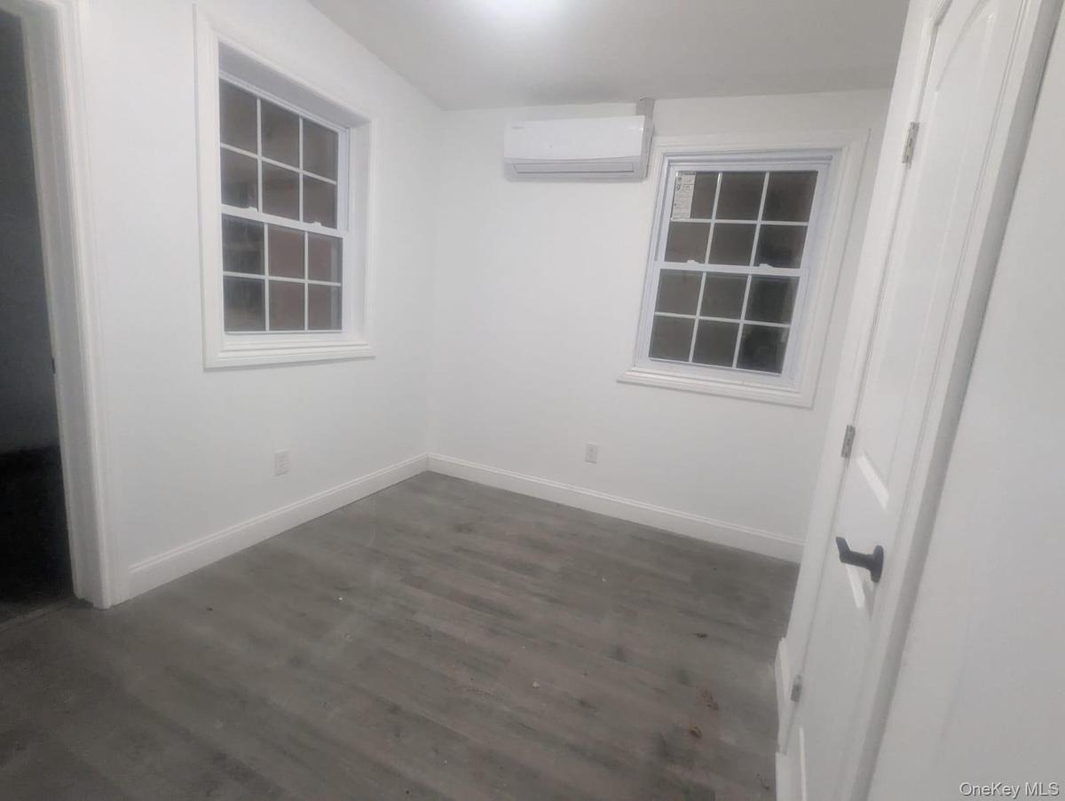 Spare room with a wall unit AC and dark wood-type flooring