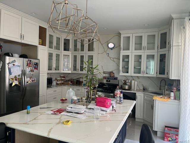 Kitchen with decorative light fixtures, white cabinets, and stainless steel appliances