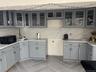 Kitchen with gray cabinetry, glass insert cabinets, black microwave, and backsplash