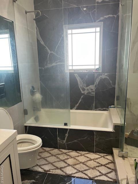 Bathroom featuring vanity, marble finish floors, and a combined bath / shower with marble appearance