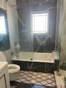 Bathroom featuring vanity, marble finish floors, and a combined bath / shower with marble appearance