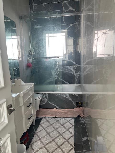 Full bathroom with vanity, enclosed tub / shower combo, and healthy amount of natural light