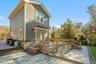 Back of property featuring a wooden deck, stone siding, and a patio area