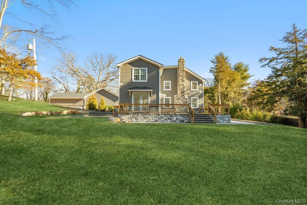 Back of property with a lawn, a chimney, and a deck