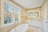 Bathroom featuring vanity, tile walls, and a freestanding bath