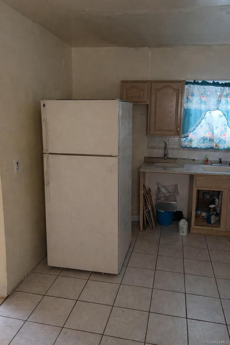 Kitchen with freestanding refrigerator, light countertops, and light tile patterned floors