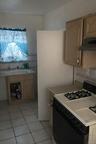 Kitchen with white range with gas cooktop, light countertops, under cabinet range hood, light tile patterned floors, and light brown cabinetry