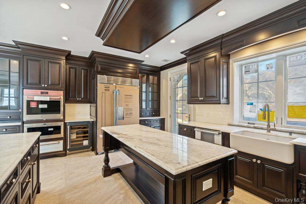 Kitchen featuring dark brown cabinetry, stainless steel appliances, wine cooler, backsplash, and recessed lighting
