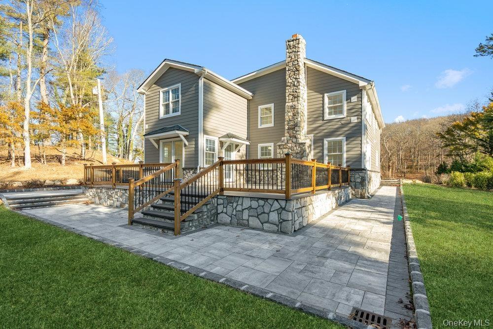 Rear view of property with a yard, a wooden deck, a patio, and a chimney
