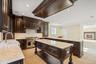 Kitchen with dark brown cabinetry, a peninsula, open floor plan, double oven range, and crown molding
