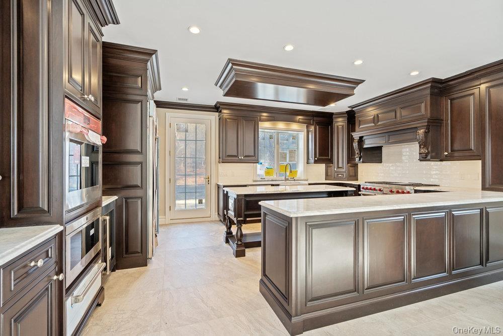 Kitchen with dark brown cabinets, a peninsula, tasteful backsplash, crown molding, and recessed lighting