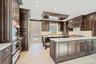 Kitchen with dark brown cabinets, a peninsula, tasteful backsplash, crown molding, and recessed lighting