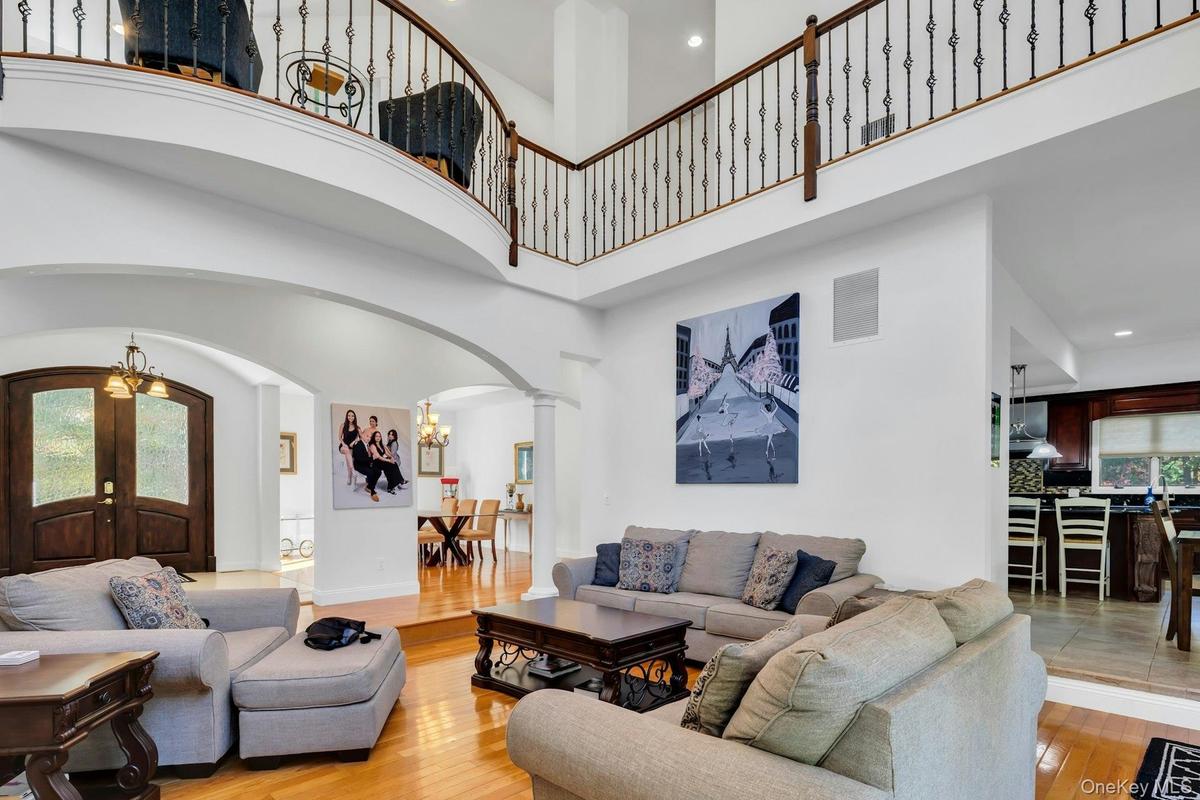 Living room featuring arched walkways, a chandelier, light wood-type flooring, recessed lighting, and a towering ceiling