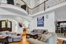 Living room featuring arched walkways, a chandelier, light wood-type flooring, recessed lighting, and a towering ceiling