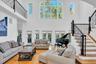 Living room with stairs, light wood finished floors, and a high ceiling