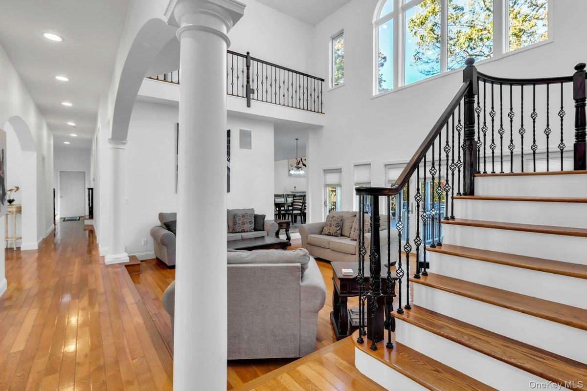 Living area with light wood-style floors, stairway, a high ceiling, recessed lighting, and decorative columns
