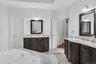 Full bath with two vanities, light tile patterned floors, and a bathtub