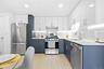 Kitchen featuring white cabinetry, appliances with stainless steel finishes, light wood finished floors, light stone counters, and decorative backspla