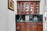 Indoor wet bar with dark stone countertops, glass insert cabinets, and tasteful backsplash