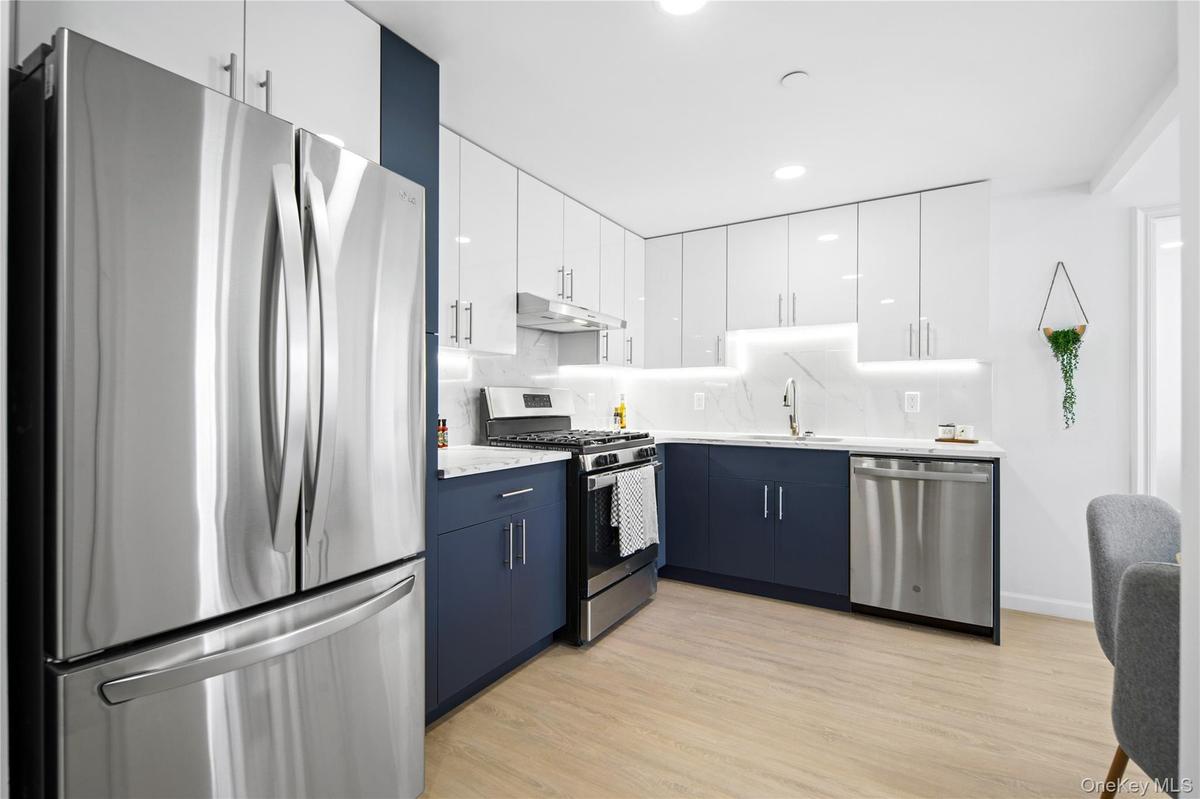 Kitchen with white cabinetry, stainless steel appliances, blue cabinetry, modern cabinets, and light wood-style floors