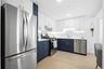 Kitchen with white cabinetry, stainless steel appliances, blue cabinetry, modern cabinets, and light wood-style floors