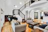 Living room with arched walkways, a towering ceiling, light wood-style flooring, french doors, and a chandelier