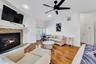 Living room with light wood finished floors, ceiling fan, recessed lighting, and a stone fireplace