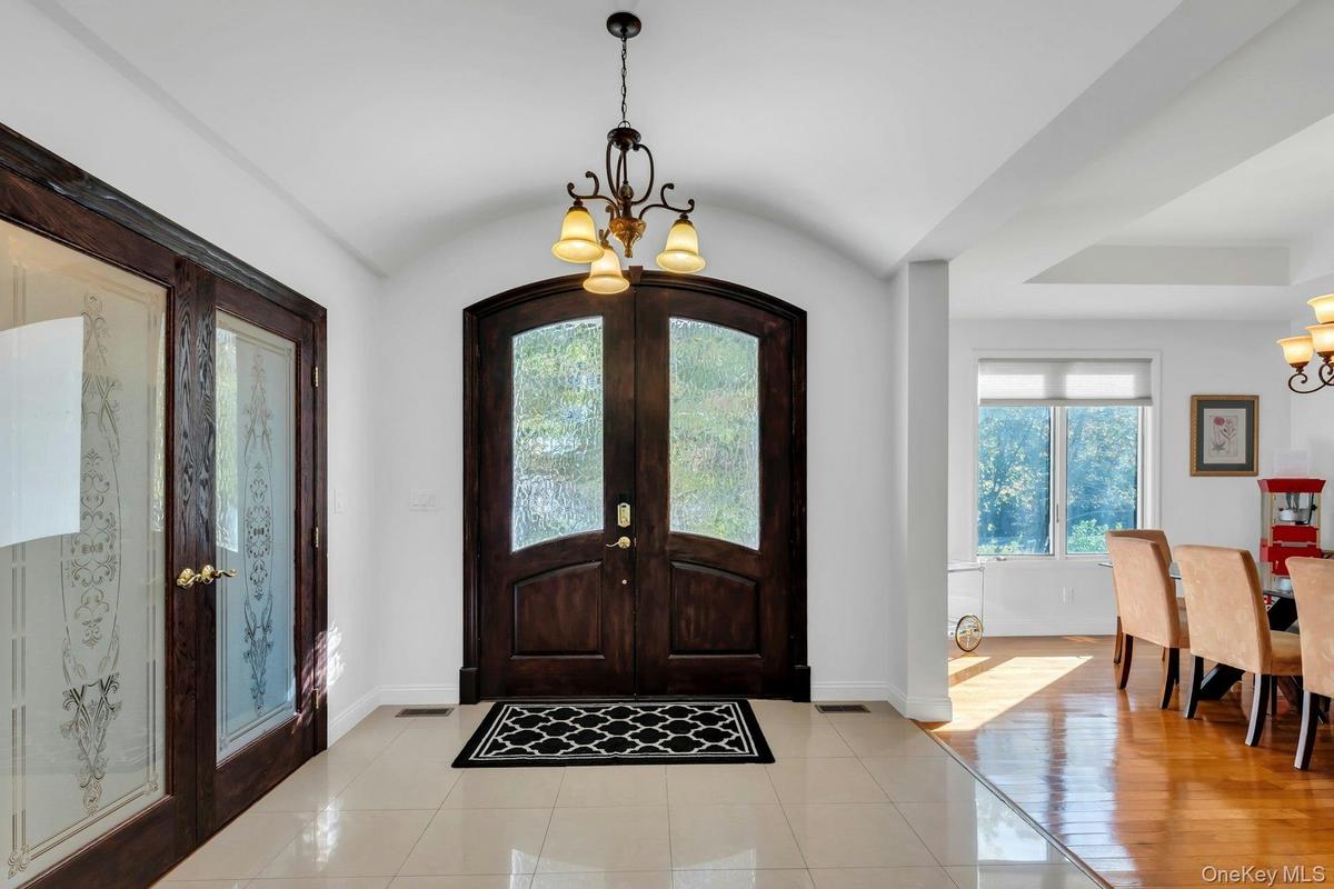 Entryway featuring a chandelier, french doors, light tile patterned floors, and lofted ceiling