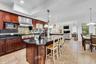 Kitchen featuring dark stone counters, a breakfast bar area, pendant lighting, range hood, and recessed lighting