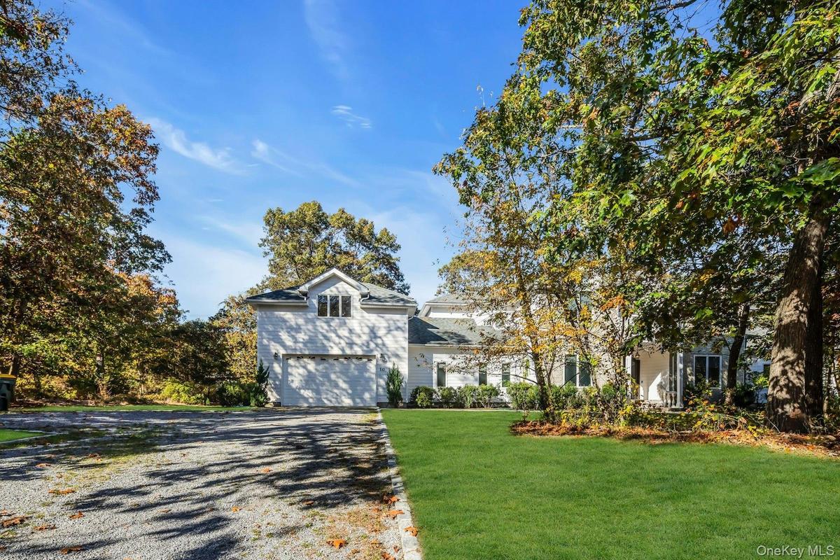 View of front of house featuring gravel driveway and a front lawn