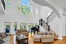 Living room with plenty of natural light, light wood-type flooring, stairs, and a towering ceiling