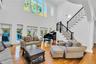 Living area with light wood-style flooring, stairs, a towering ceiling, and decorative columns