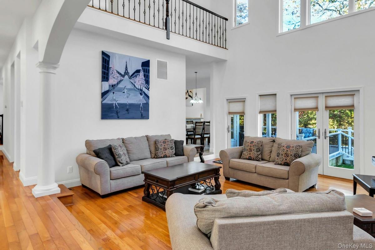 Living area featuring hardwood / wood-style floors, ornate columns, arched walkways, and a high ceiling