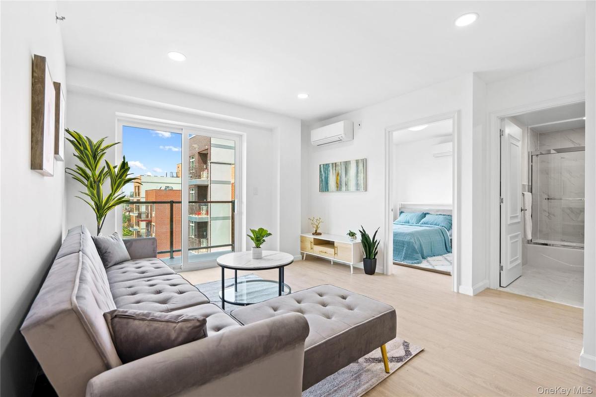 Living area featuring light wood-style floors, recessed lighting, and an AC wall unit
