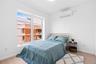 Bedroom with a wall mounted AC and light wood finished floors