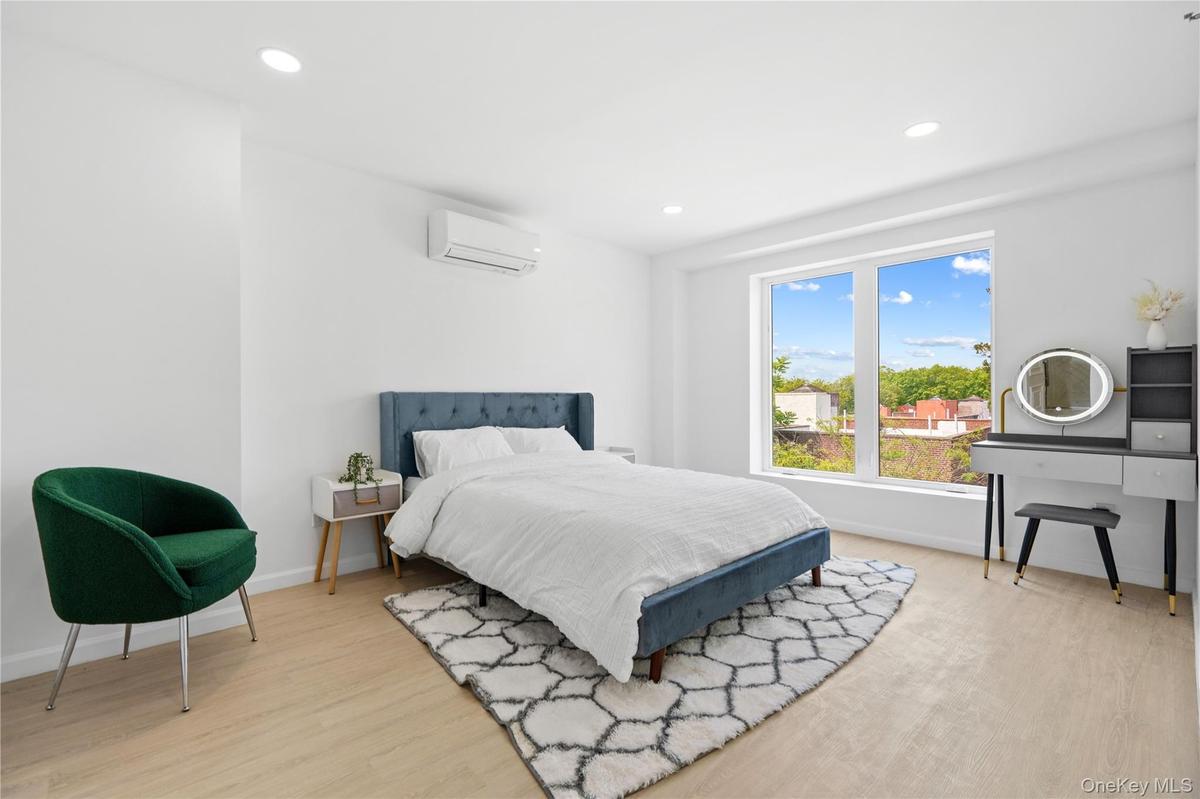 Bedroom with light wood-type flooring, a wall unit AC, and recessed lighting