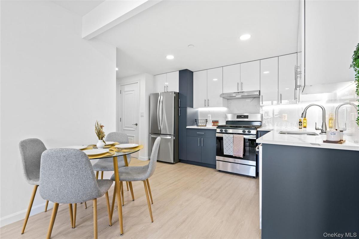 Kitchen featuring white cabinetry, stainless steel appliances, light wood-style floors, light stone counters, and decorative backsplash