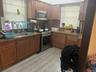 Kitchen with stainless steel appliances, light wood-type flooring, decorative backsplash, and dark stone countertops