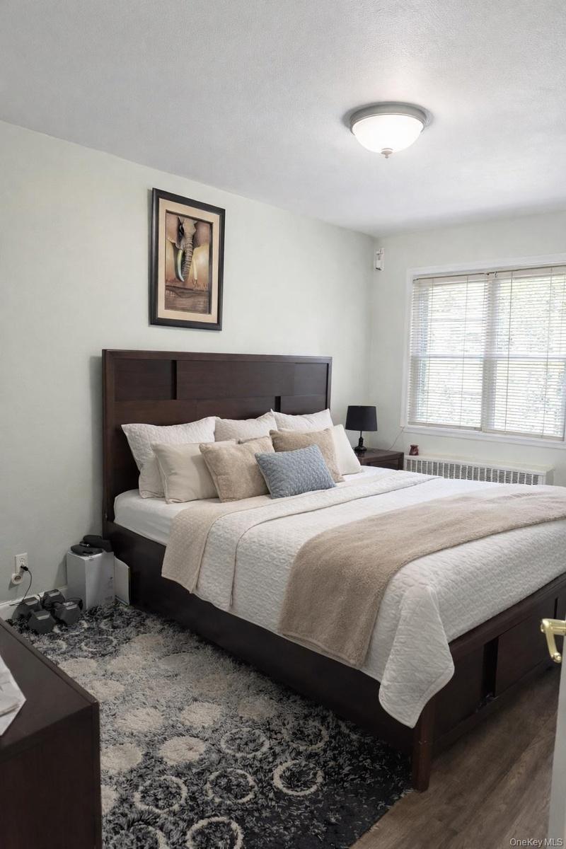 Bedroom with radiator heating unit and wood finished floors