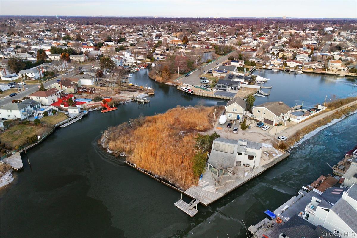 Aerial view of property and surrounding area with a nearby body of water and nearby suburban area