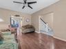 Living room with wood finished floors, stairs, and ceiling fan