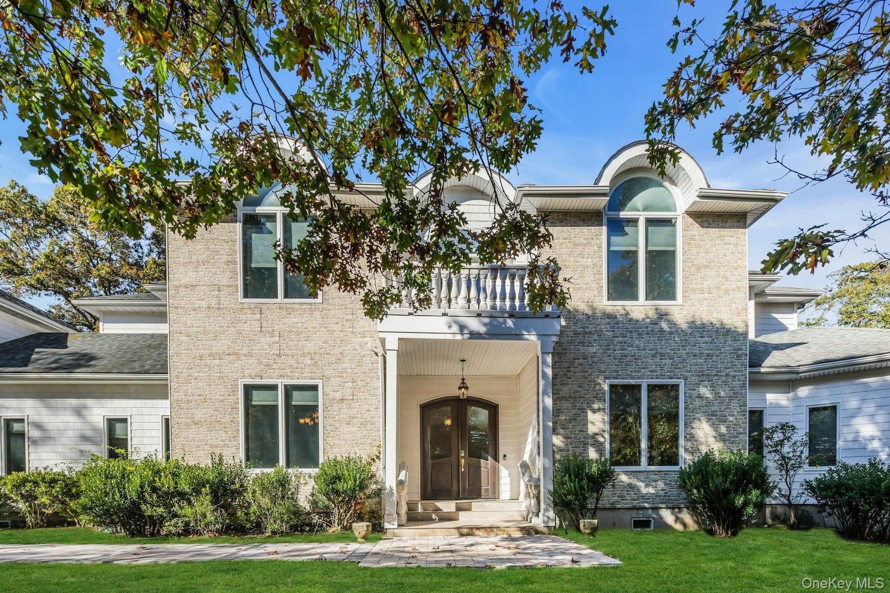 Traditional-style home featuring a front yard, brick siding, and a balcony